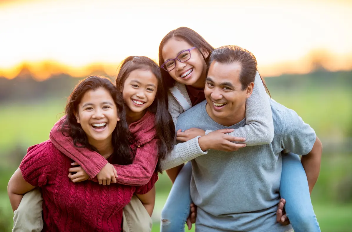 Smiling family of four outdoors, representing affordable family health insurance in Texas