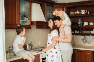 Happy family of four bonding together in their kitchen, representing the security and care provided by Texas Family Health Insurance Plans.