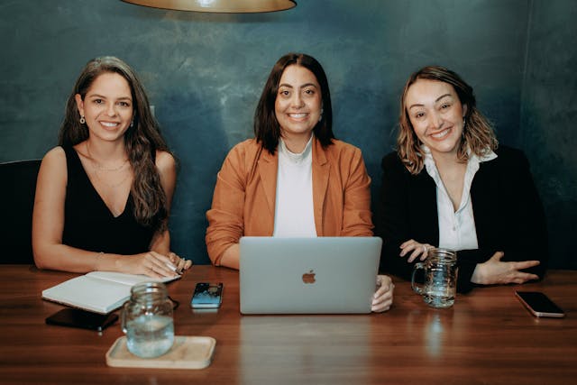 Three women business owners reviewing small business health insurance requirements on laptop together