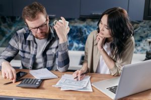 Couple reviewing health savings account rules and paperwork together at kitchen table with calculator and laptop