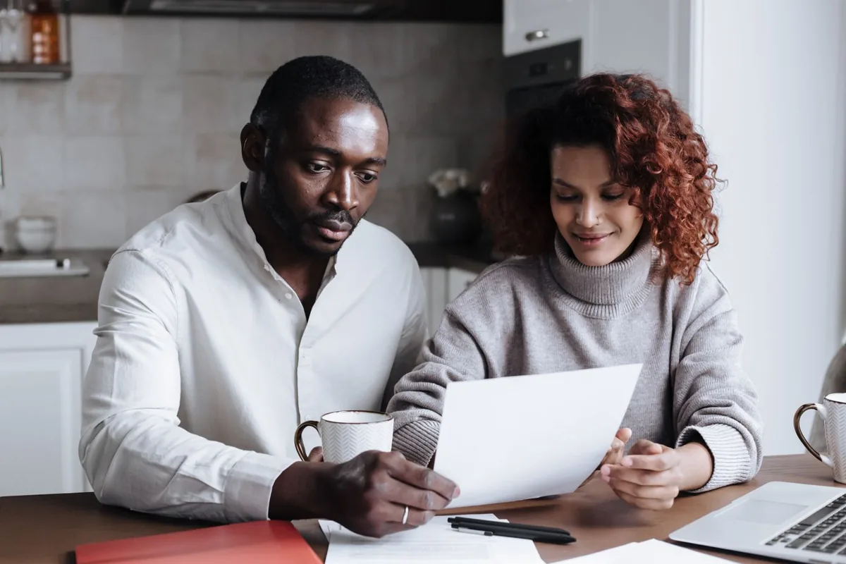 Couple comparing COBRA open enrollment options against a private plan quote at home
