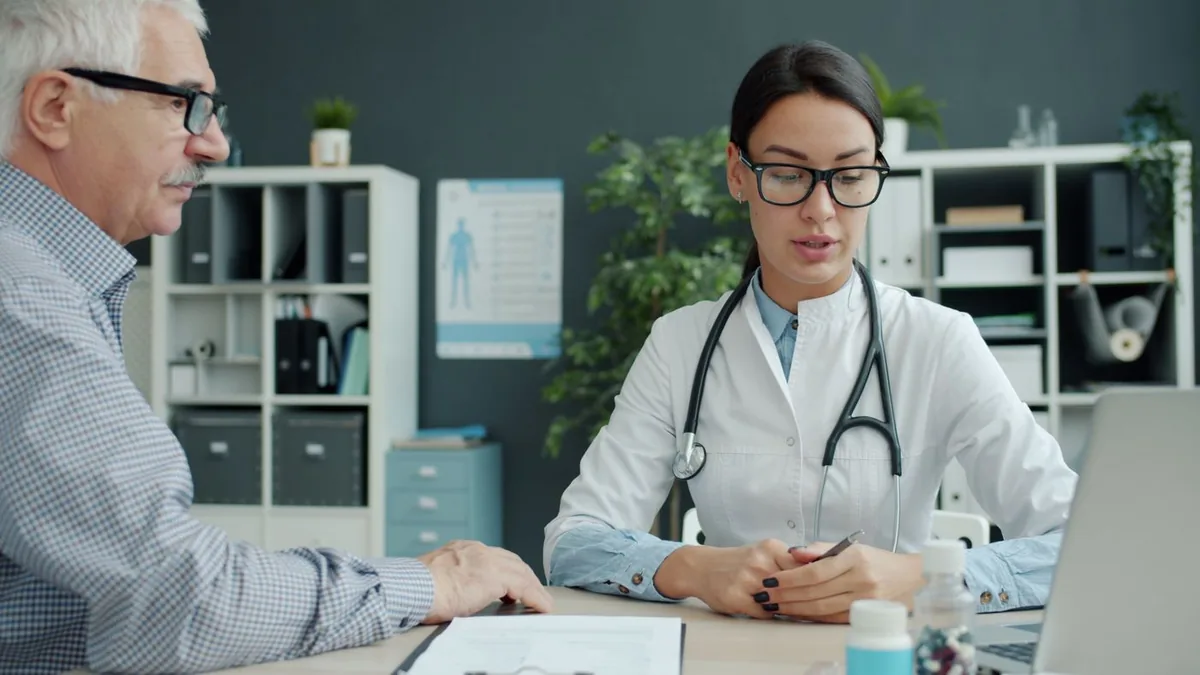 A doctor talking with a patient, illustrating how to choose health insurance plan coverage that includes your doctors in network