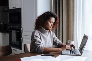 A woman reviewing plan details on her laptop at home, a guide on how to choose health insurance plan during open enrollment