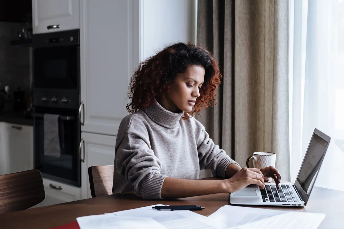 A woman reviewing plan details on her laptop at home, a guide on how to choose health insurance plan during open enrollment
