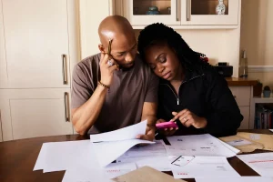 Texas couple reviewing bills at the kitchen table, asking is health insurance cheaper during open enrollment