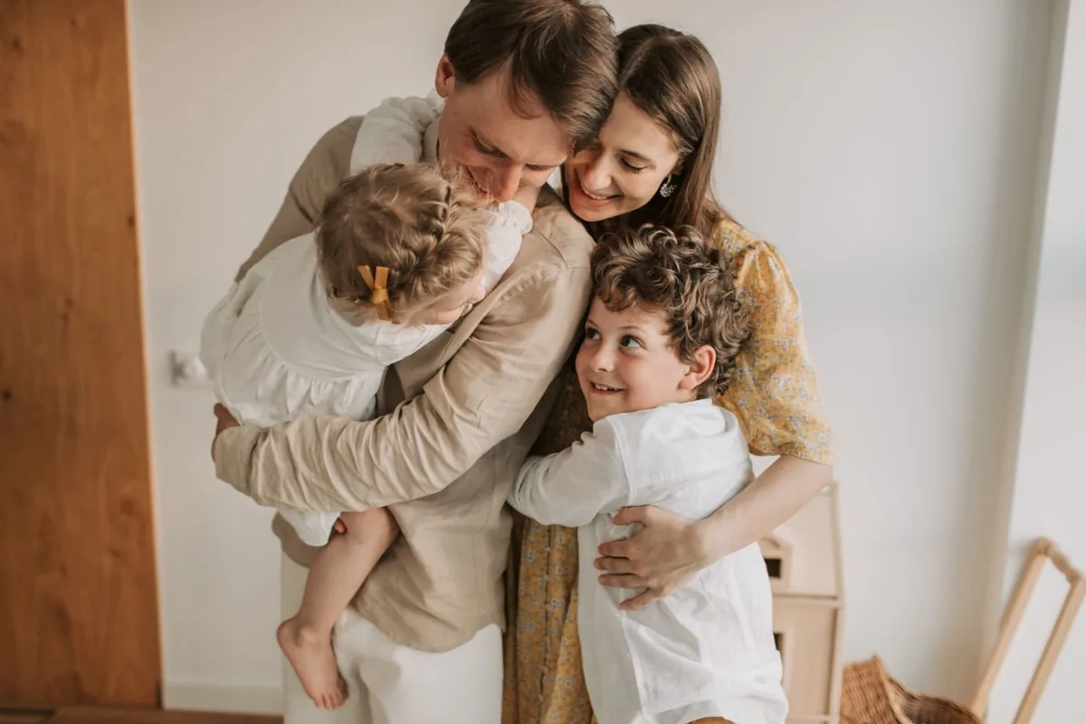 Family of four hugging at home after sorting out coverage when they missed open enrollment for health insurance