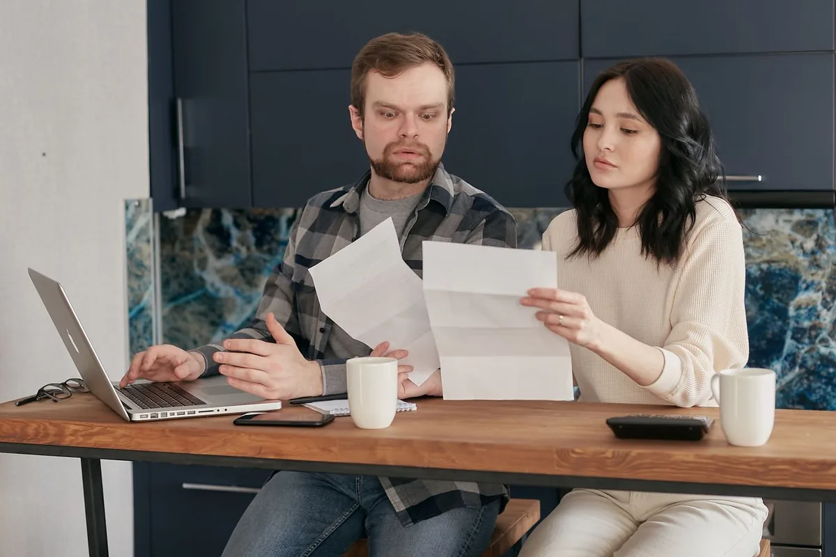 Couple at a kitchen table reading the letters that prove a qualifying life event health insurance claim, such as a coverage end date notice