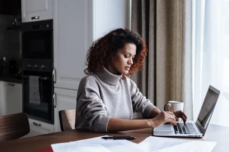 A woman reviewing plan details on her laptop at home, a guide on how to choose health insurance plan during open enrollment