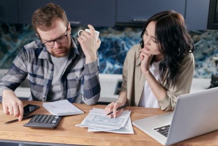 Couple reviewing health savings account rules and paperwork together at kitchen table with calculator and laptop
