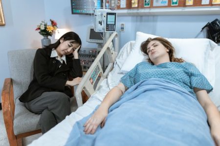 Person who missed open enrollment for health insurance recovering in a hospital bed beside a concerned loved one