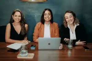 Three women business owners reviewing small business health insurance requirements on laptop together