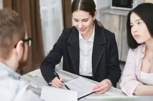 Insurance broker reviewing Blue Cross Blue Shield of Texas health plan options with a young couple at a meeting table