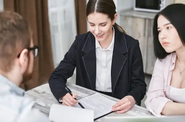 Insurance broker reviewing Blue Cross Blue Shield of Texas health plan options with a young couple at a meeting table